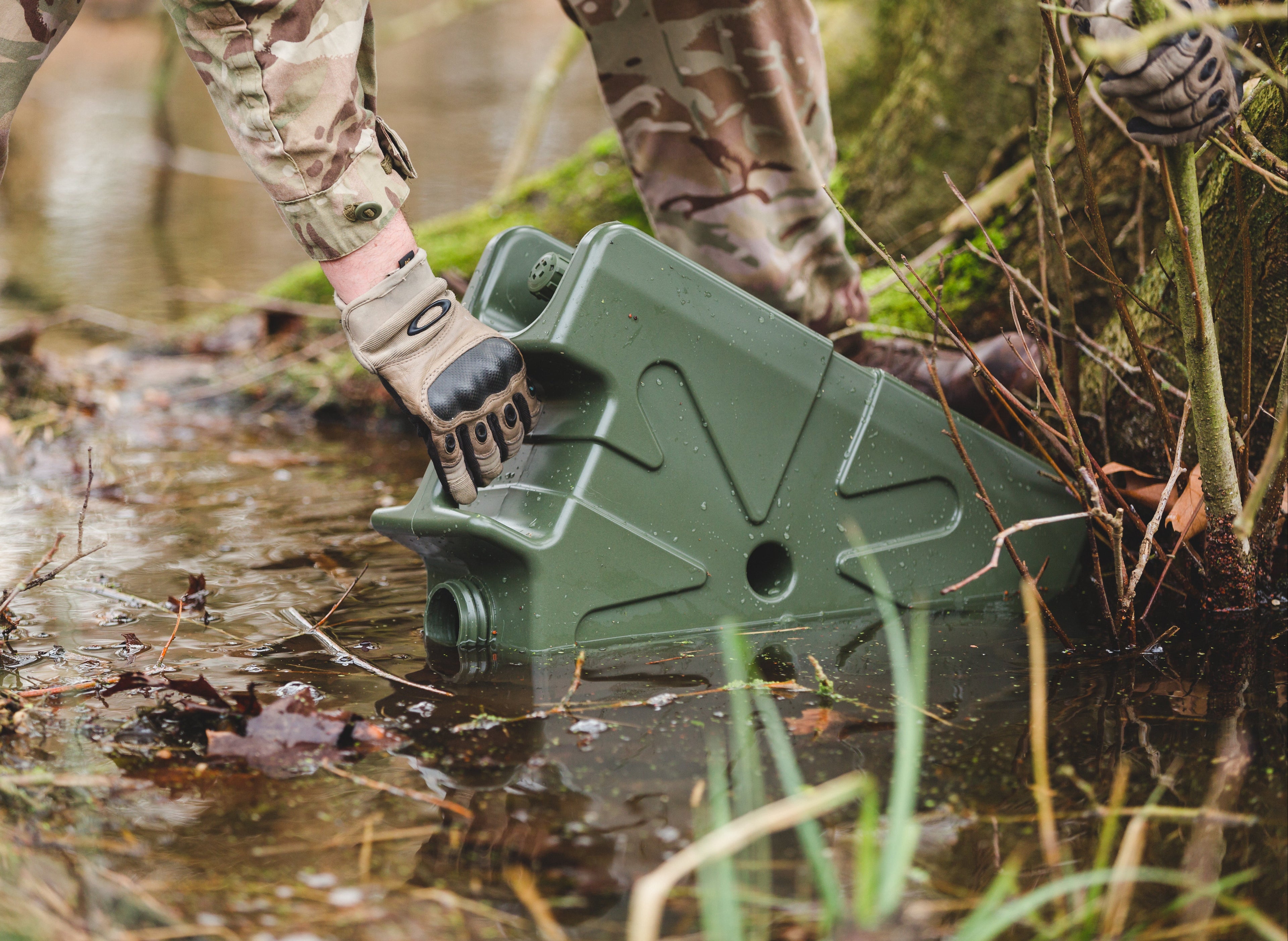 Soldier filling a green LifeSaver Jerrycan from a stream
