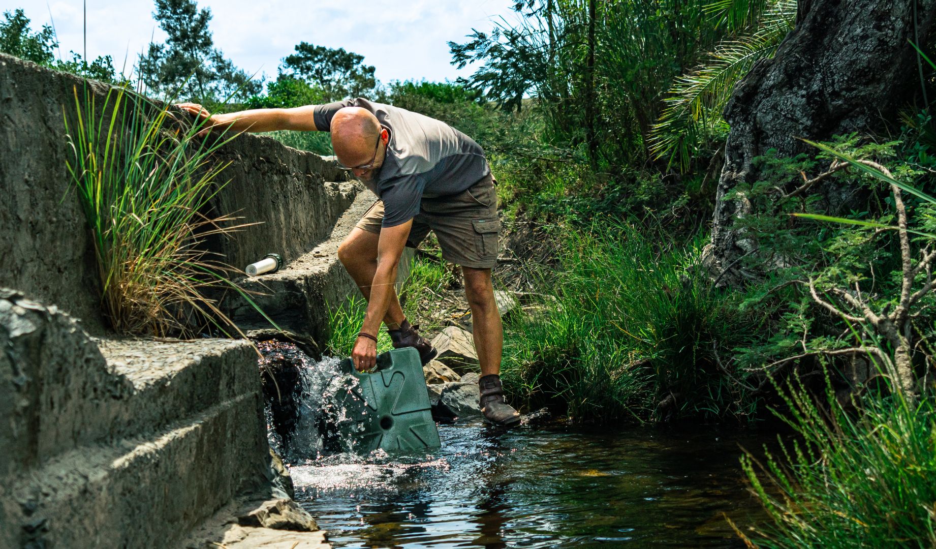 Filling a green jerrycan from a water spout