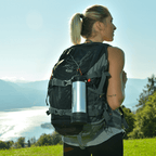 Woman with a backpack and insulated bottle in a mountainous landscape